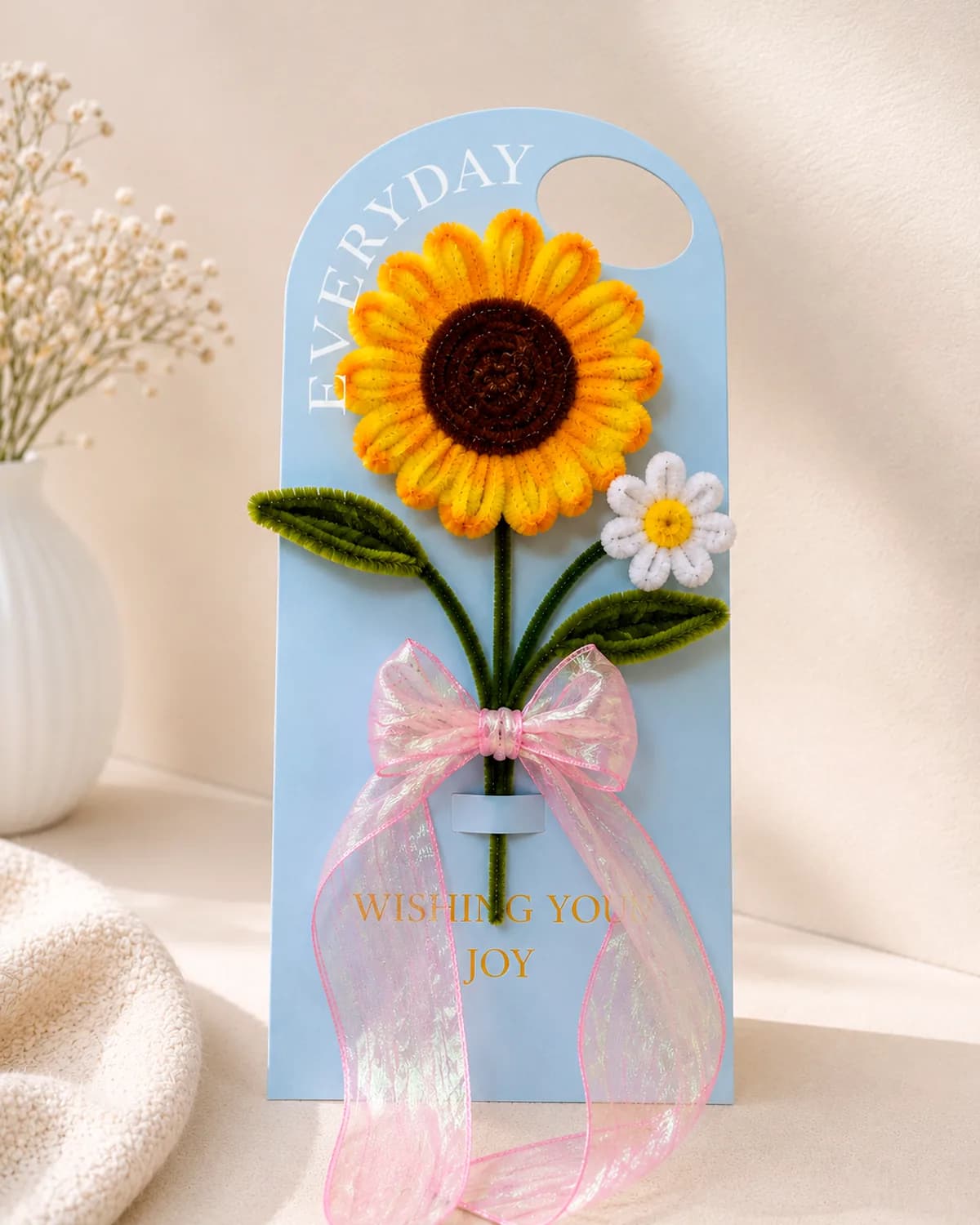 handmade pipe-cleaner flower mounted on a gift card, finished with a ribbon bow
