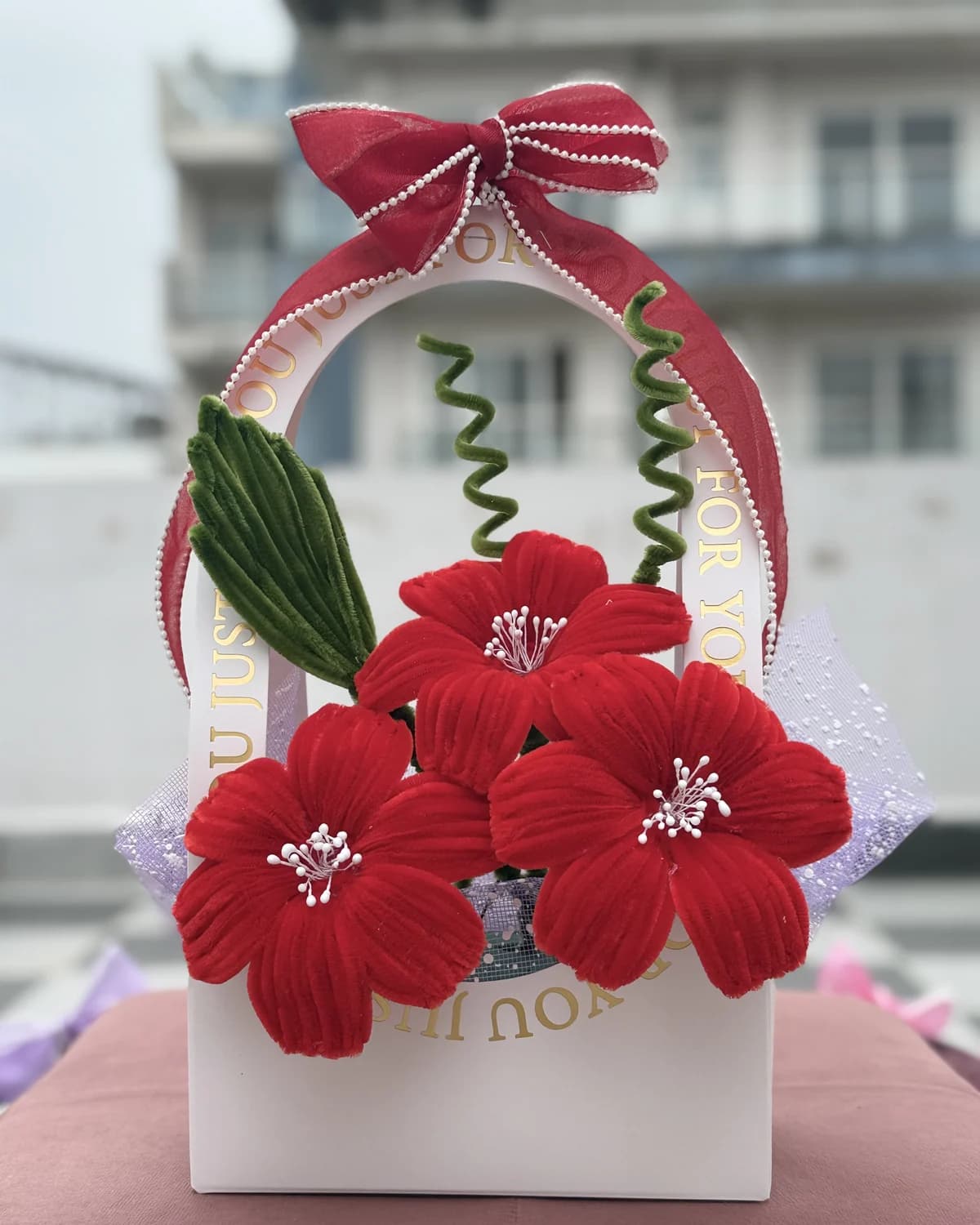 handmade chenille flowers standing in an arched "just for you" carrier bag tied with an organza bow — red blooms, view 2