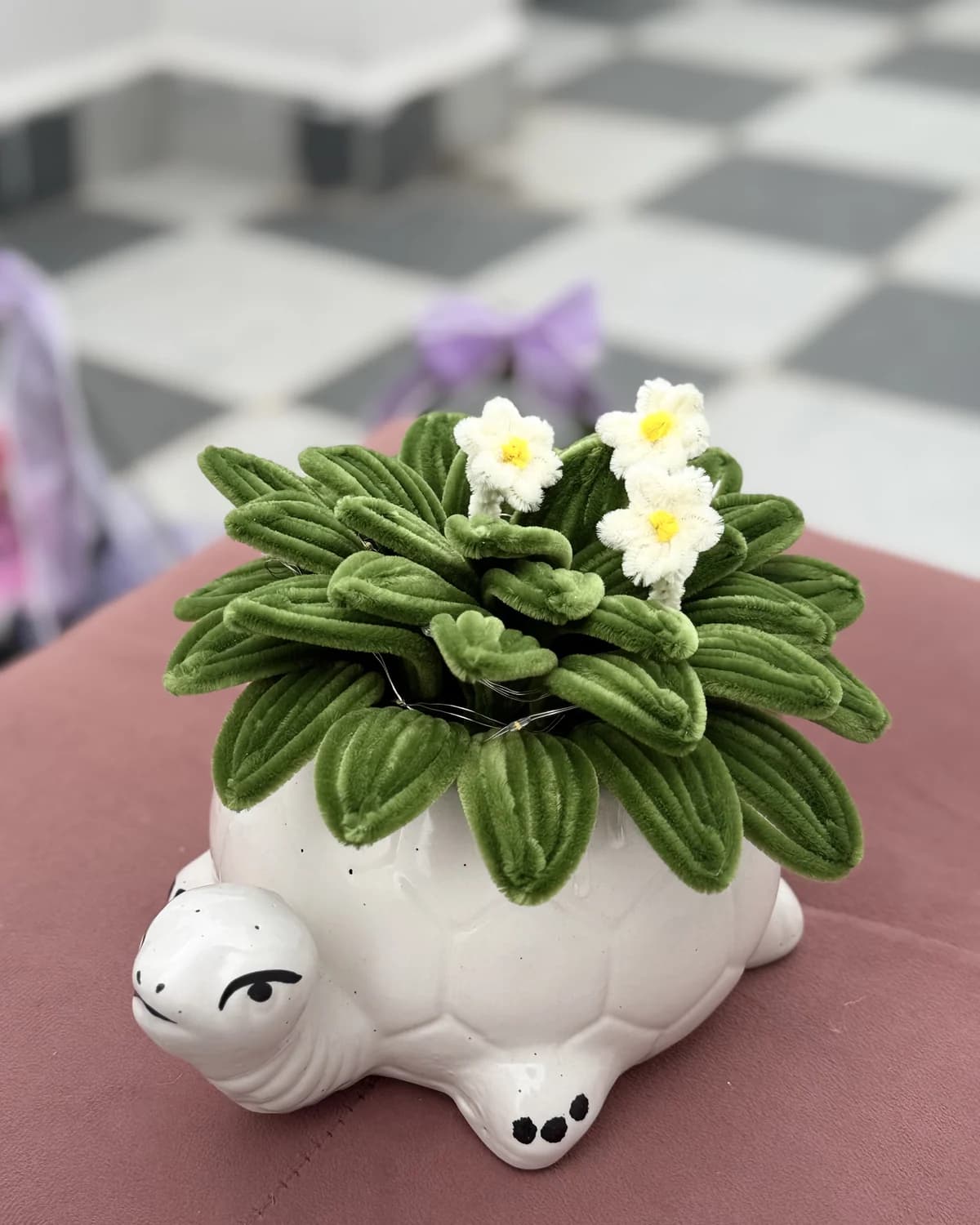handmade chenille succulent with small white flowers, planted in a white ceramic turtle pot