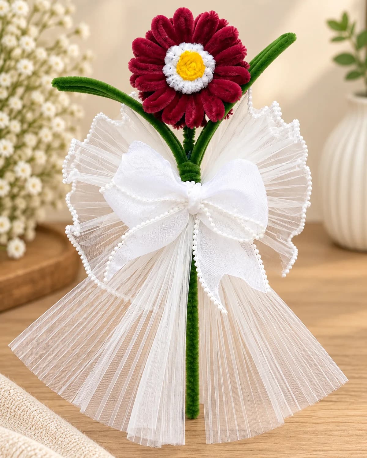 single handmade chenille flower on a long wrapped stem, in a pleated tulle wrap with a pearl-edged bow — burgundy bloom